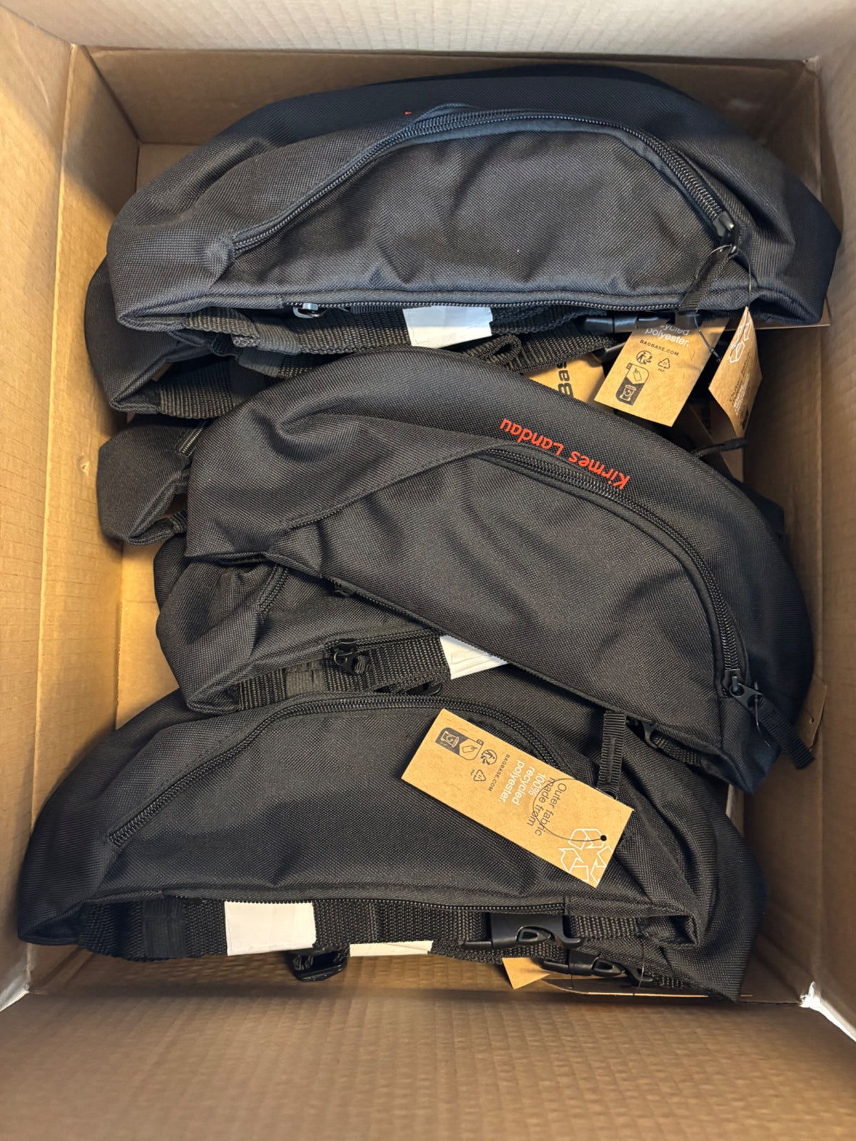 Schwarze Bauchtaschen mit rotem Kirmes Landau Schriftzug im Versandkarton